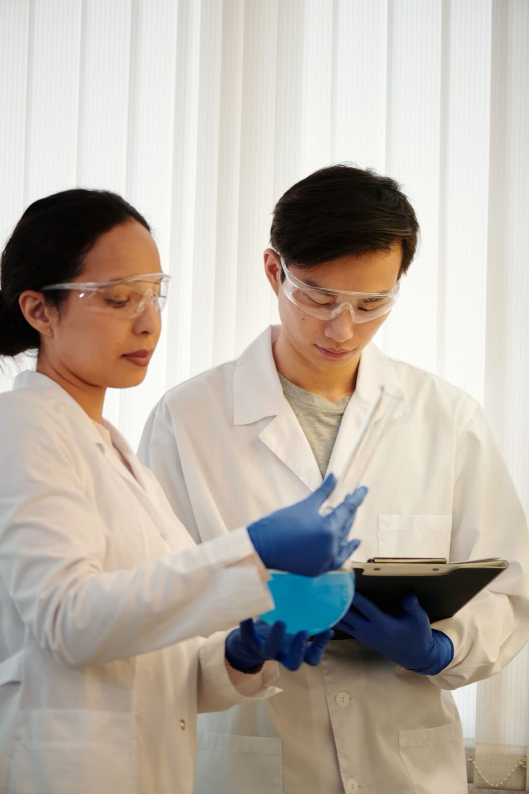 Two scientists in lab coats examining a sample