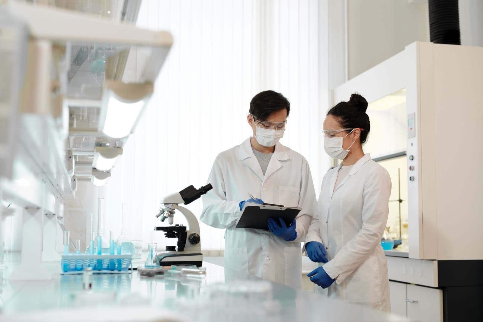 Two scientists discussing work beside a microscope